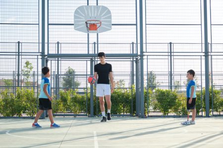 Couch playing football with two students.